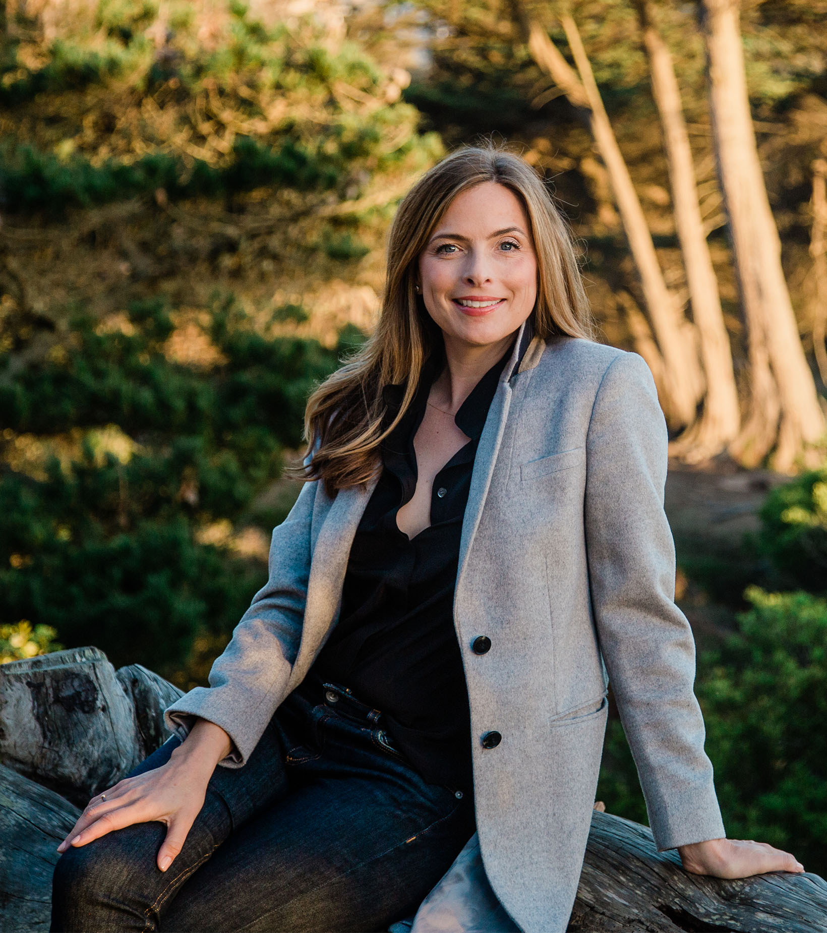 View of Shannon Hughes sitting outside, featuring trees in the background