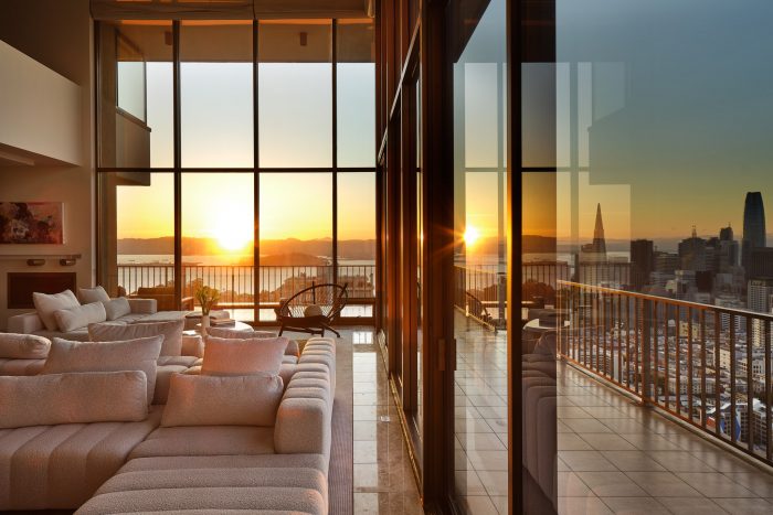 999 Green St open living area with plate glass walls and view of SF skyline at sunset