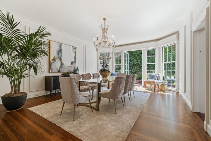 View of a large formal dining room with open French doors leading outside