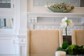 Close-up of a dining room chair and the white wood mantel 