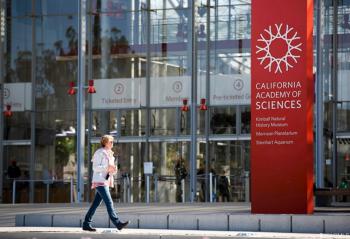A person walking by a sign for California Academy of Sciences 