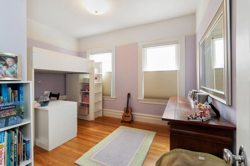 View of a pale purple bedroom with wood floors 