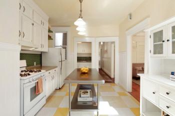 Long-view of the kitchen showing white cabinetry and white trim