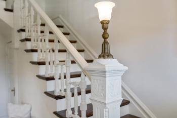 View of white stair rail with a vintage light 