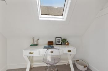 A desk positioned beneath a skylight in a white room