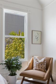 A chair positioned near a large window and live plant 