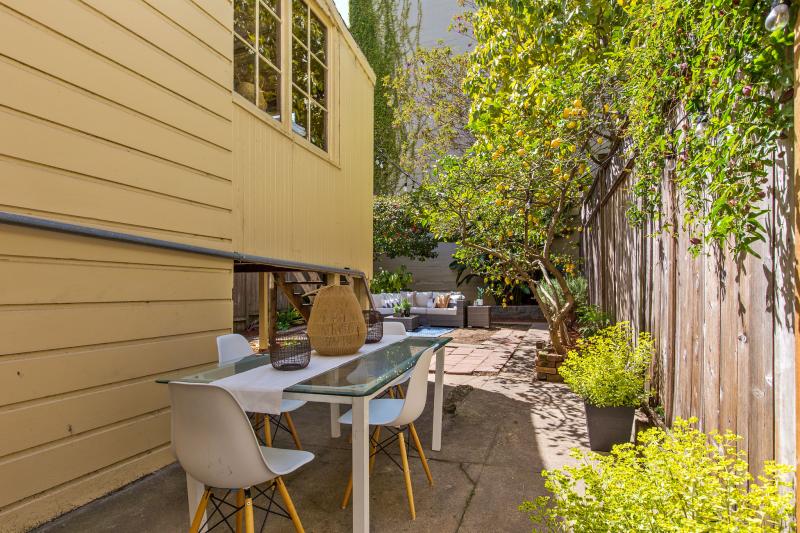 Side yard at 32 Hartford Street, featuring a long table and chairs for out-door dining 