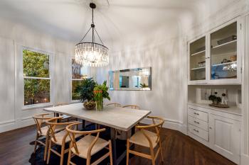 Dining area, featuring a beautiful chandelier, large windows, and white built-in cabinet