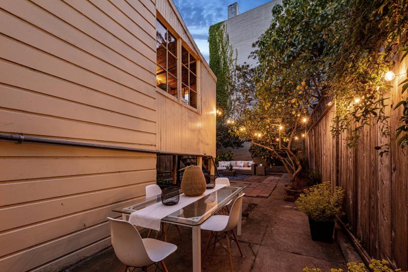 Side yard at 32 Hartford Street, featuring a long table and chairs at night