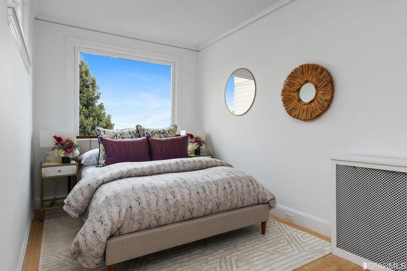 A bed positioned under a large window in 2832 Union Street