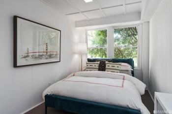 Lower bedroom with bed positioned beneath two windows at 2832 Union Street