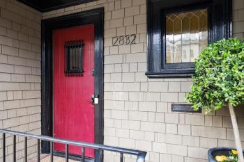 A red front door with dark wood frame, leading into 2832 Union Street