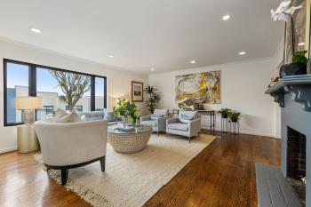 Living room with wood floors, white walls, and large windows, featured at 450 Los Palmos Drive