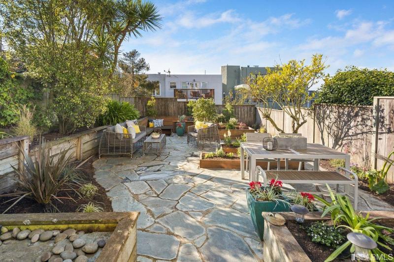 View of the rear patio featuring raised flower beds and outdoor dining space