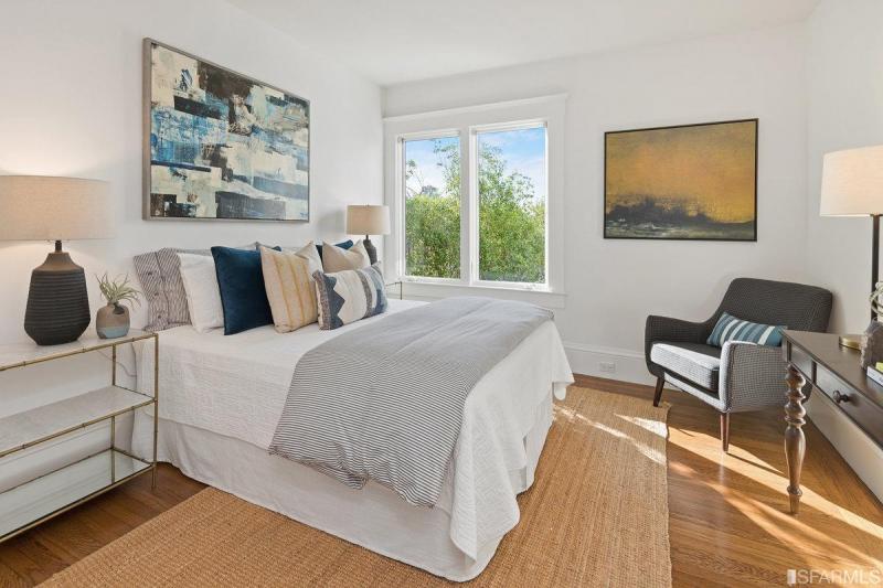 Spacious bedroom with white walls and wooden floors