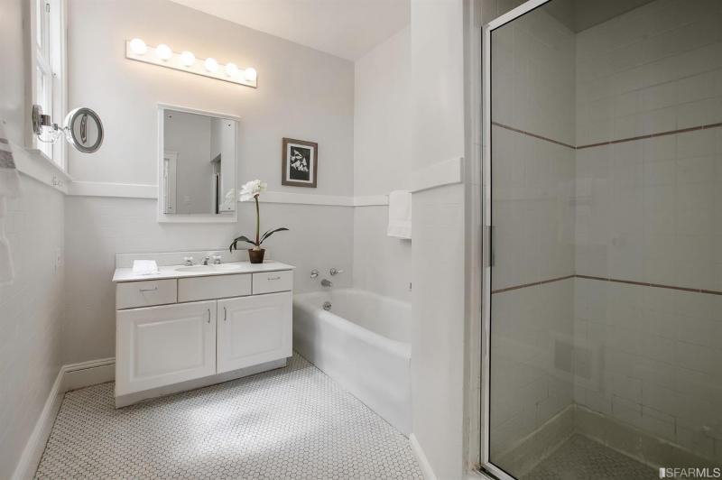 Bathroom with white vanity, bath, and shower with glass door