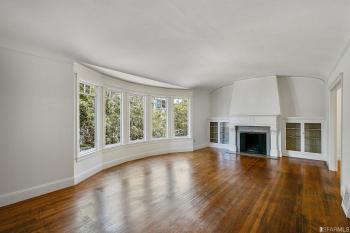 View of a large living room with wood floors, a fireplace, and 5 bay windows