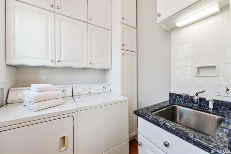 View of the laundry area with over-head cabinets and a sink in unit two