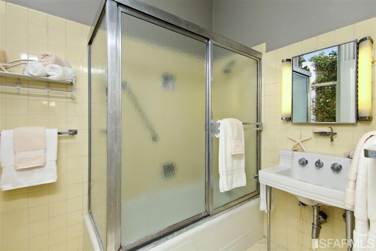 Bathroom with yellow tile and bath with glass doors